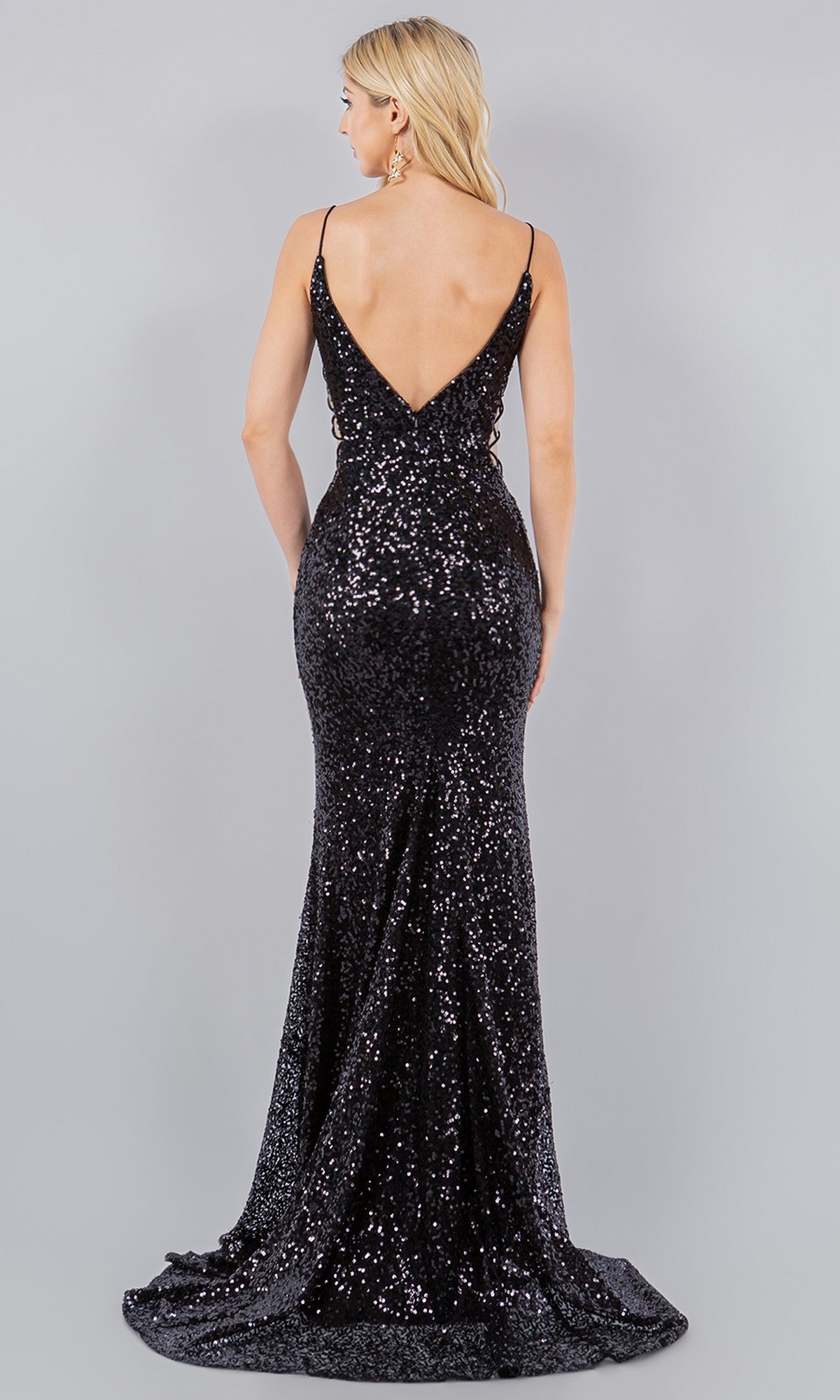 A woman models the Sparkly Sequin Prom Dress: Cinderella Couture 8078J—floor-length, black, with thin straps and a deep V-back—standing against a plain grey background.